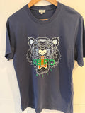 Navy blue t-shirt with a tiger logo and 'KENZO' branding on a wooden hanger.